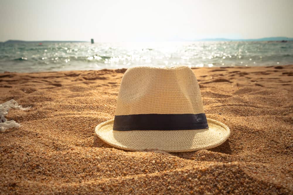 This is a close look at a fedora on a sandy beach.