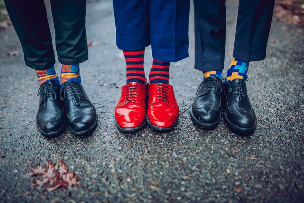 A row of men wearing colorful patterned socks.