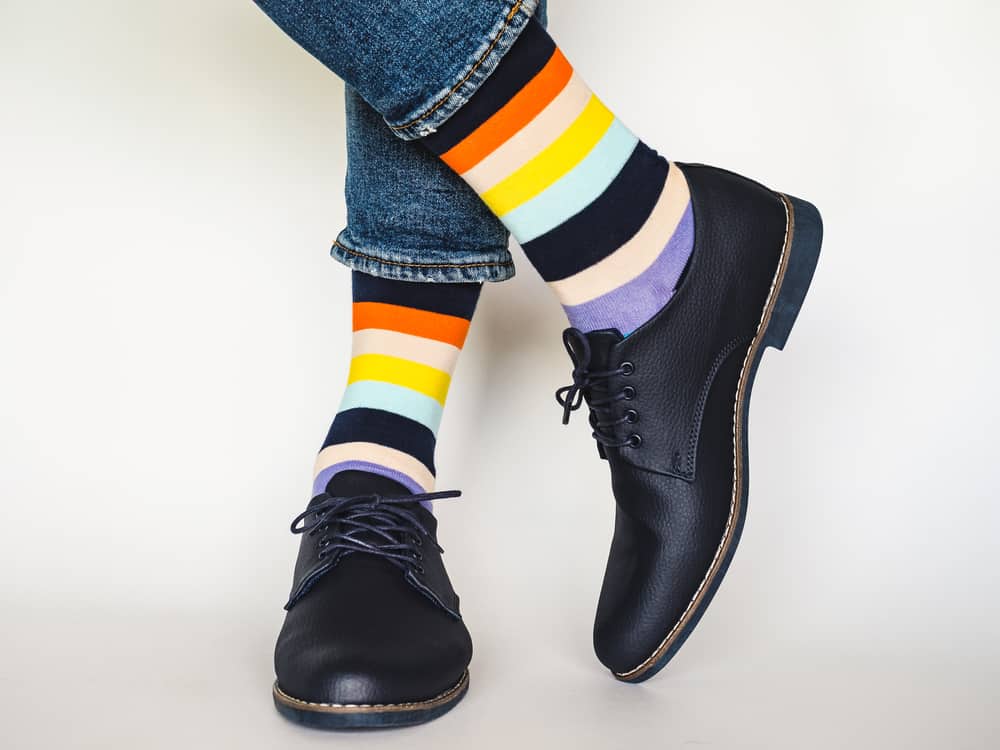 A close look at a pair of colorful striped socks paired with black leather shoes.