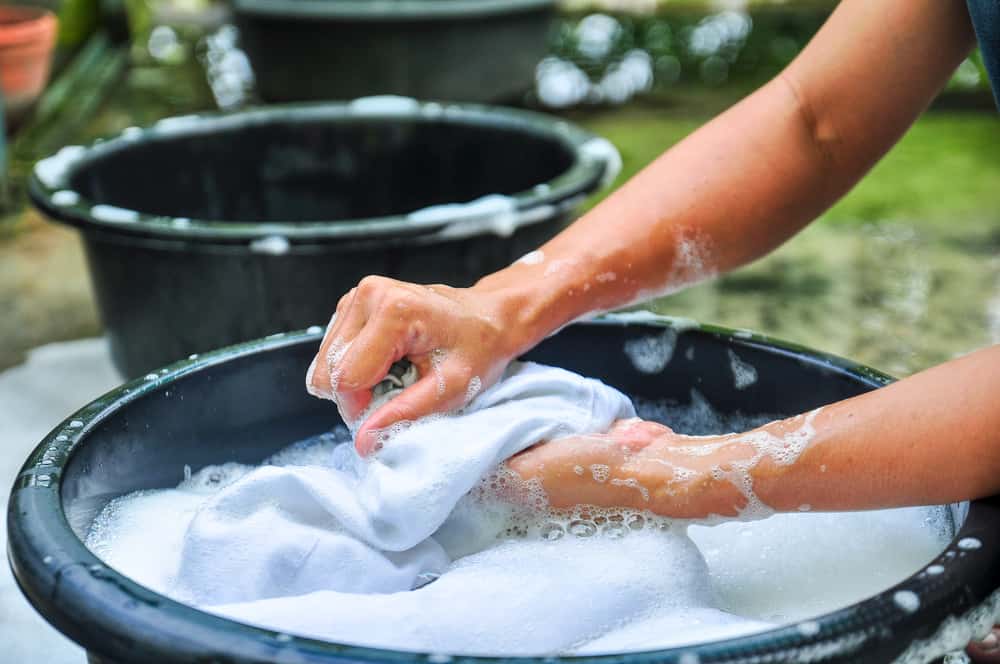 A person hand-washing the clothes on a basin.
