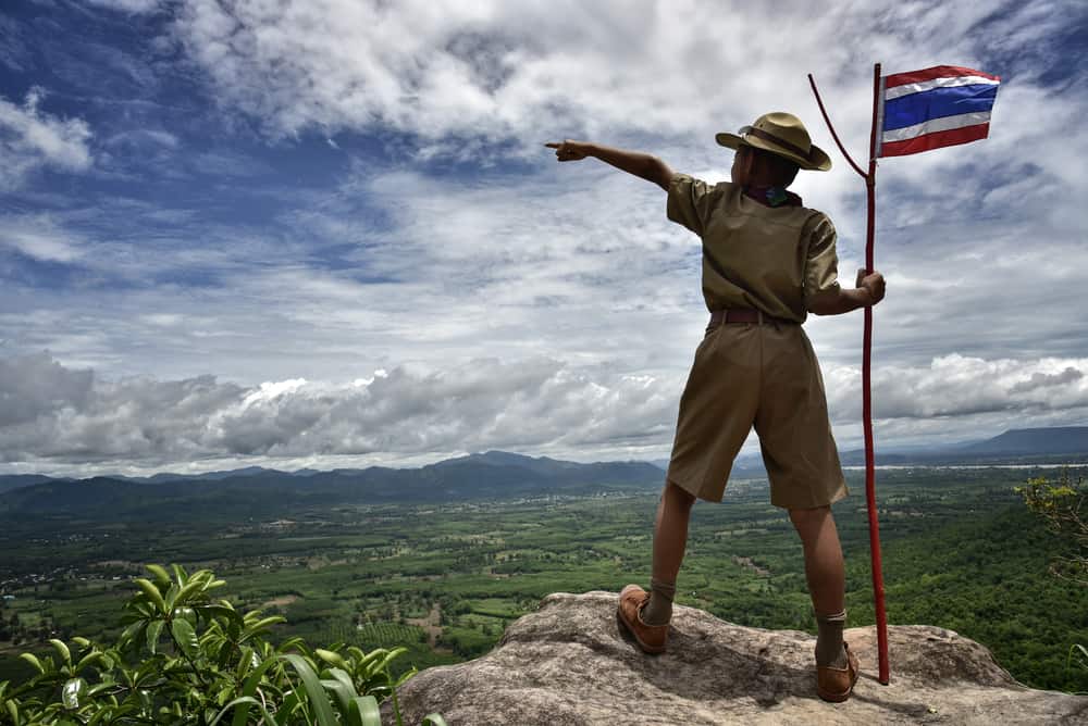 A boy scout standing on top of a hill.