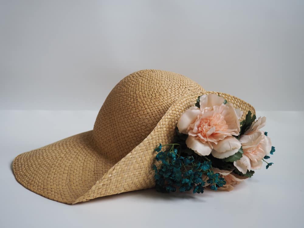 Shantung straw hat graced with peach flowers and blue leaves.