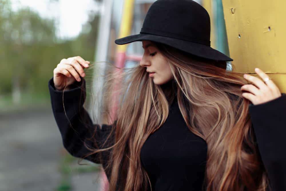 A woman wearing a black sweater and black fedora.