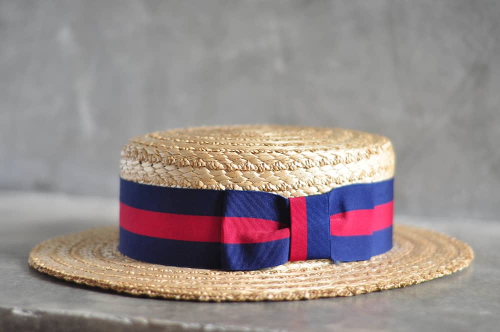 This is a close look at a woven straw boater hat with a red and blue band.