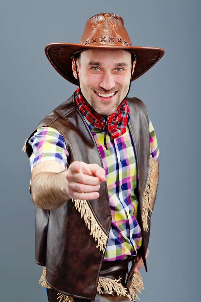 This is a man wearing a brown leather cowboy hat with his leather outfit that has frills.