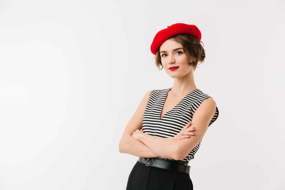 A woman wearing a red velvet beret with her striped shirt.