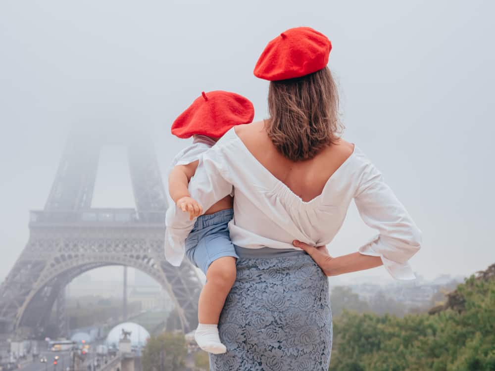 A mother and son wearing matching red berets while gazing at the Eiffel Tower.