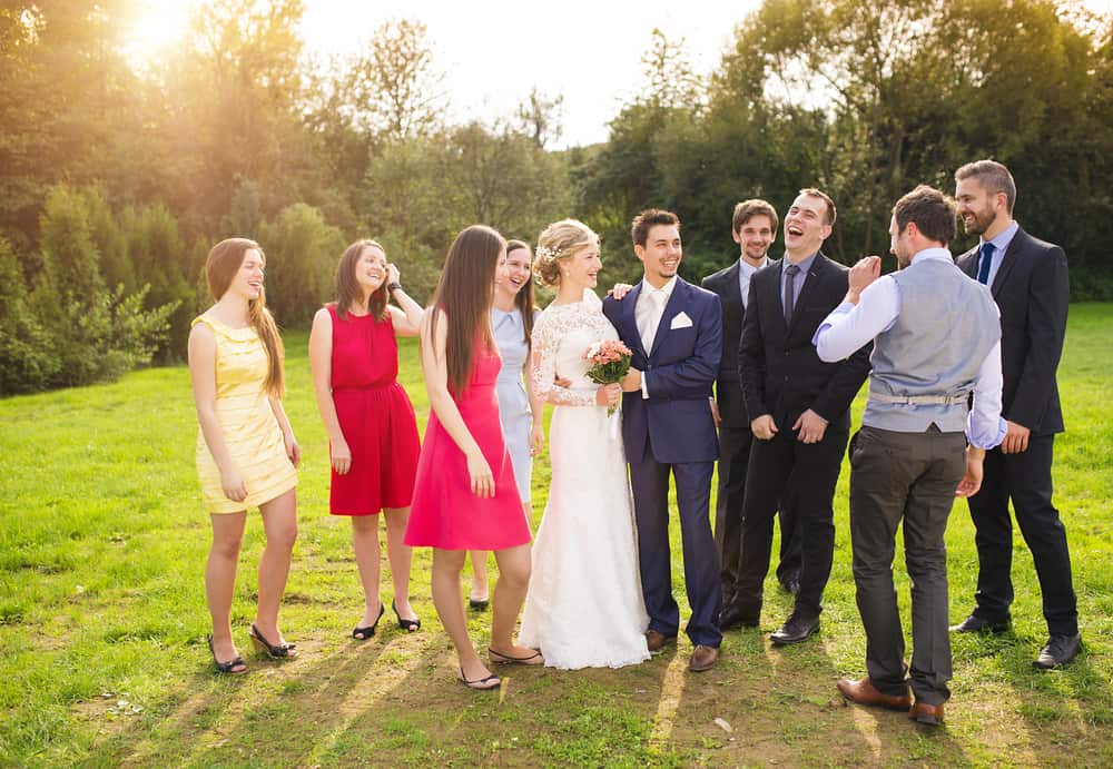 A newly wed couple laughing with their friends with the men wearing suits and the women wearing dresses.