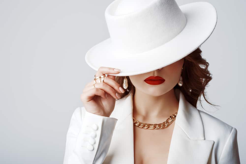A woman wearing a white suit and matching white fedora.