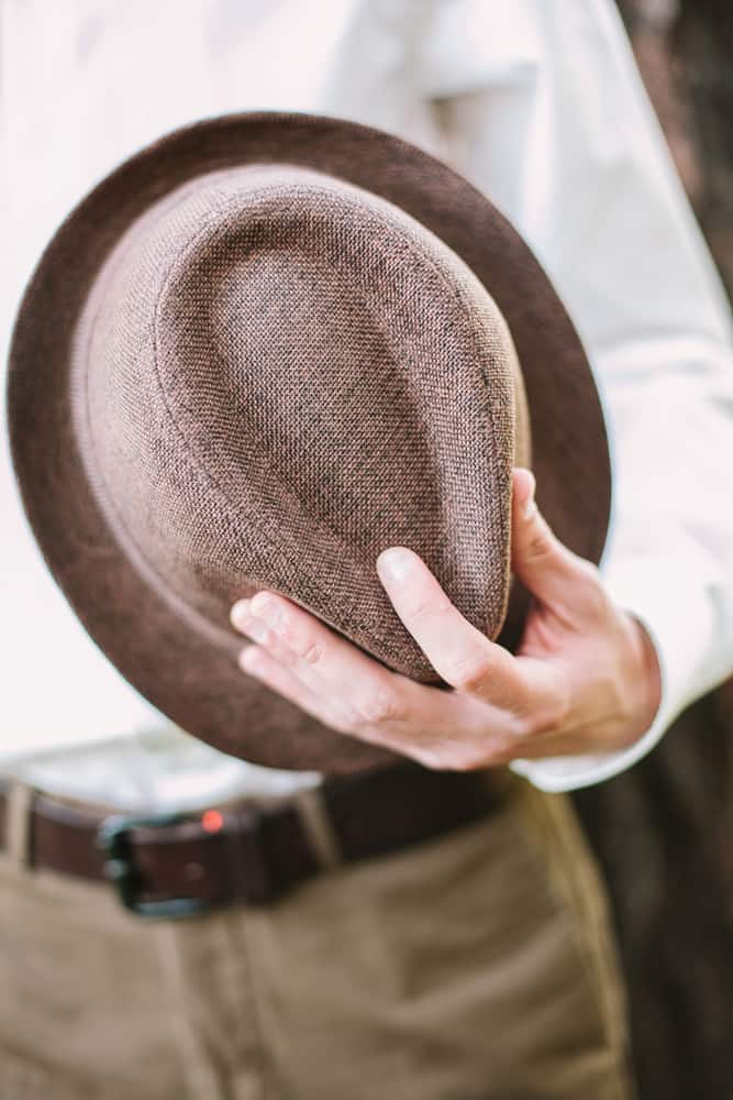 A man holding a trilby fedora hat.