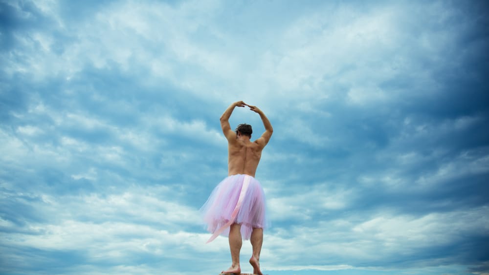 A man wearing a ballerina tutu skirt while dancing.