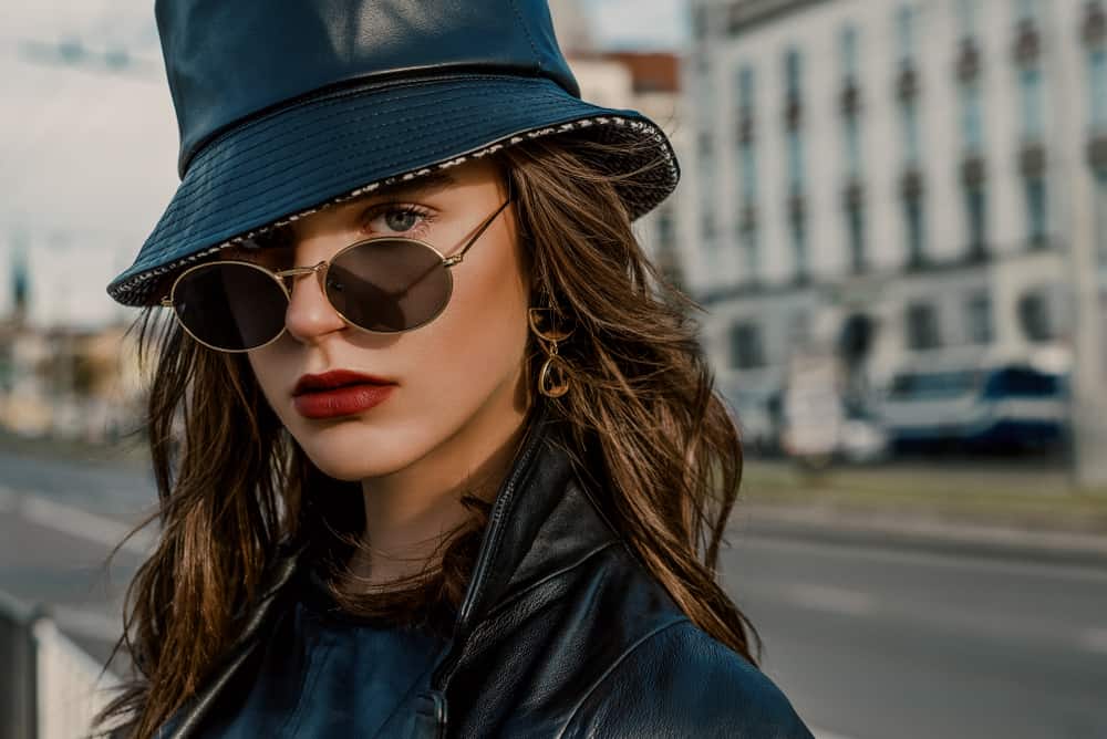 This is a close look at a woman wearing a leather jacket and a leather bucket hat.