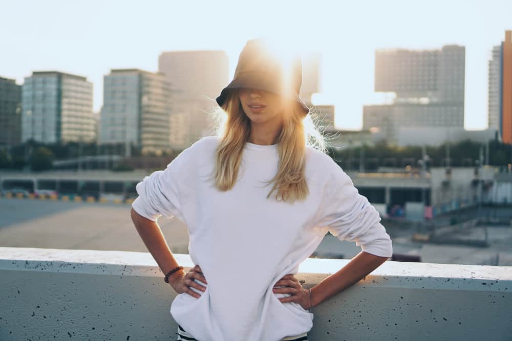 This is a woman wearing a white oversized shirt with her bucket hat.