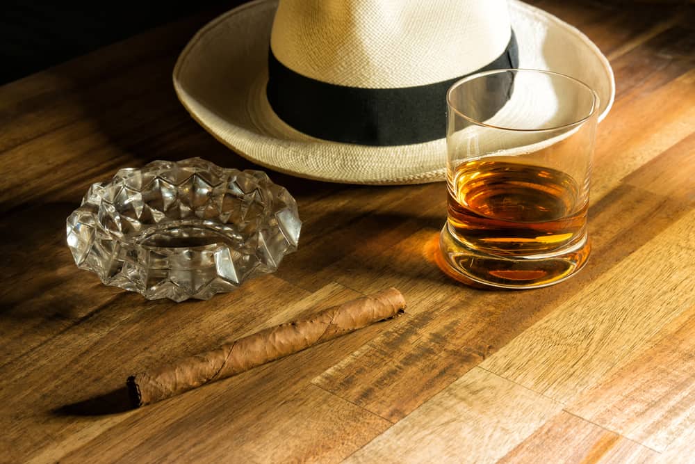 A close look at a Panama hat, a cigar and a glass of rum.