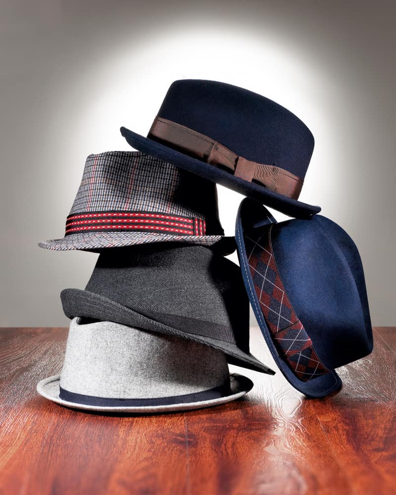 A close look at a stack of fedoras on the floor.
