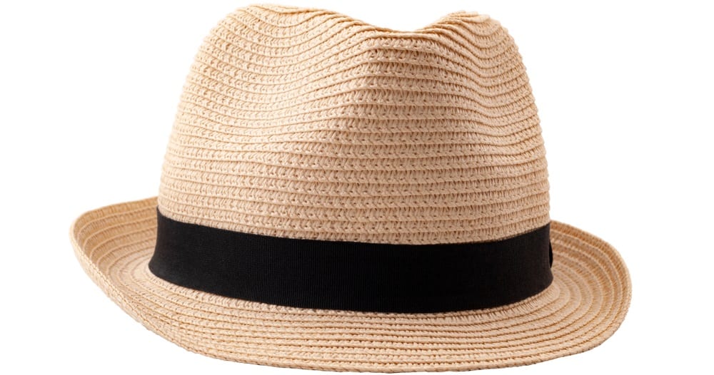 A close look at a woven straw fedora hat that has a black band.