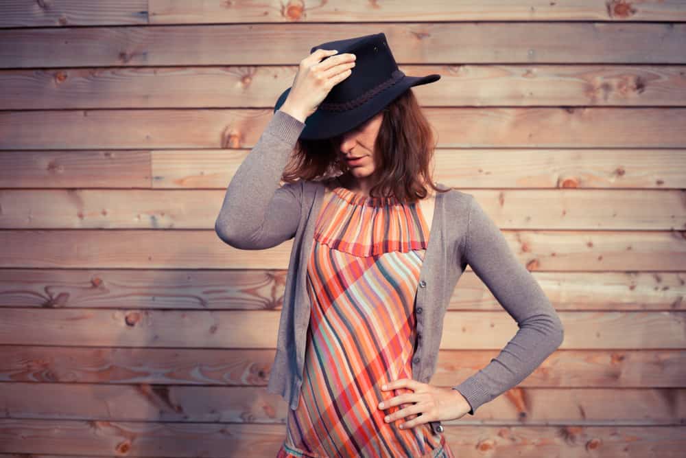 A close look at a woman wearing a colorful patterned dress and a dark fedora hat.