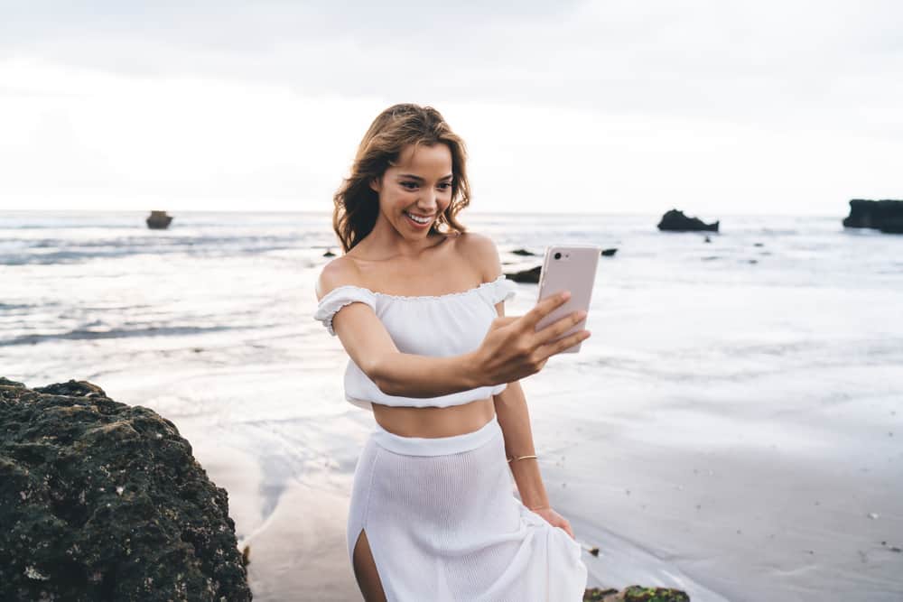 This is a close look at a woman wearing a slip skirt at the beach while taking a selfie.