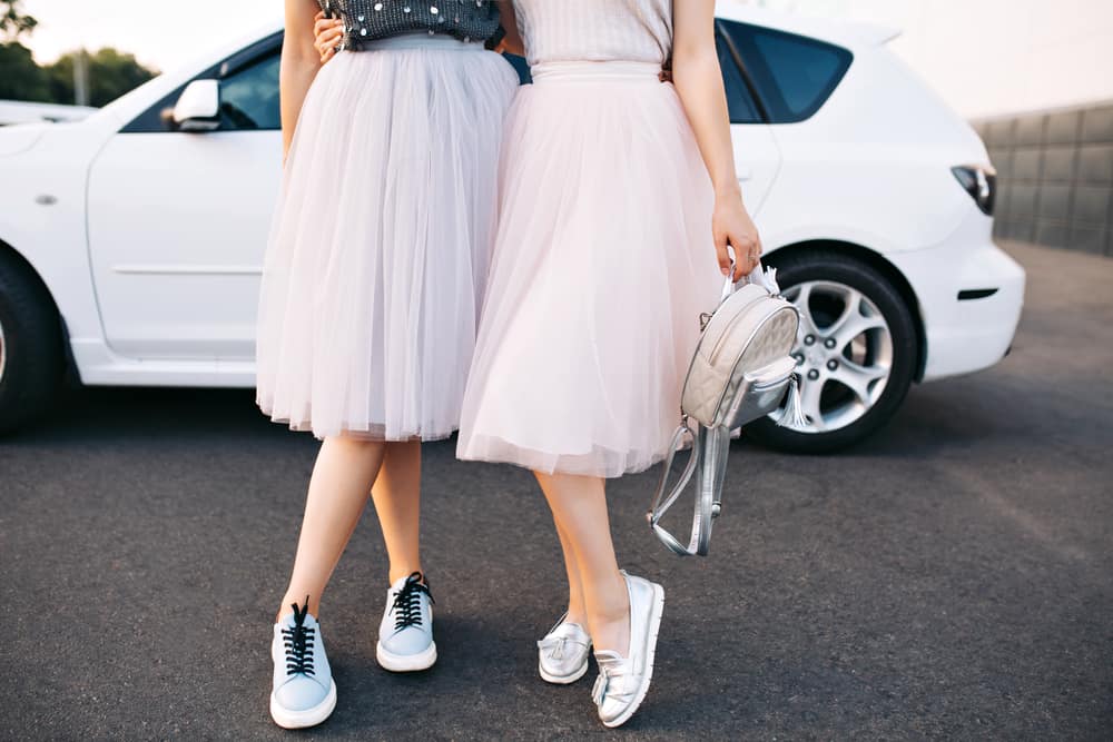 This is a close look at a couple of women wearing tulle skirts and sneakers.