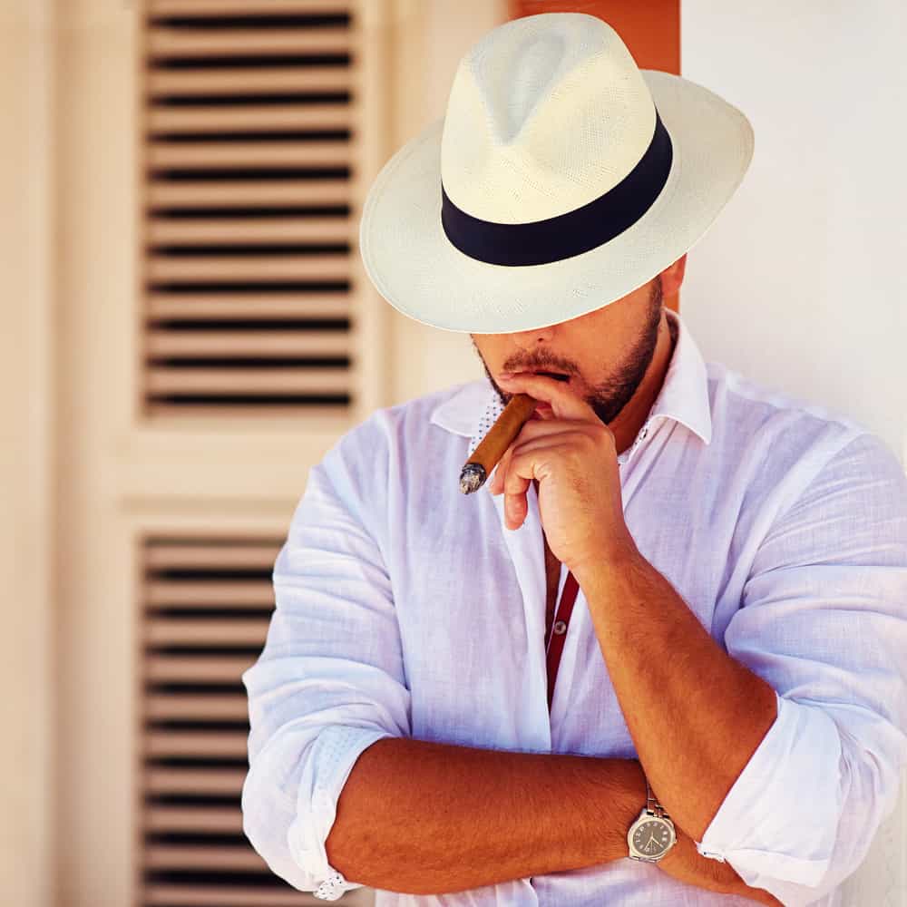 This is a man wearing a panama hat while smoking his cigar.