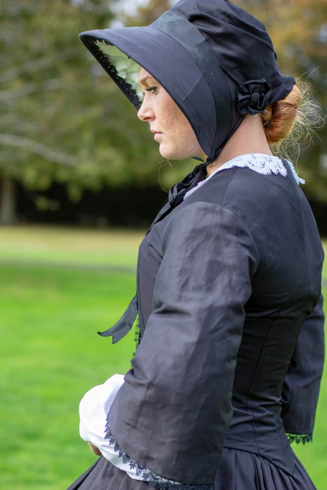 This is a woman wearing a vintage mourning dress with matching mourning bonnet.